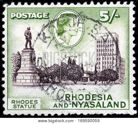 LUGA RUSSIA - SEPTEMBER 18 2015: A stamp printed by RHODESIA AND NYASALAND shows image portrait of Queen Elizabeth II against view of Cecil Rhodes Statue circa 1959