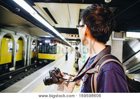 Tourist Man Waiting For Subway At Station Hilding Map With Camera