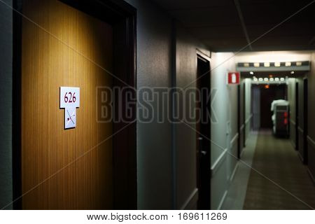 Dark hallway with doors of hotel rooms, illuminated 626 humber with symbol no smoking
