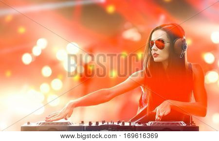 Portrait of pretty young DJ playing music on light background