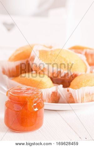 Breakfast with plumcake and apricot jam on white dish.