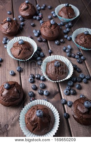 Chocolate cupcakes with blueberries on wooden table. Top view