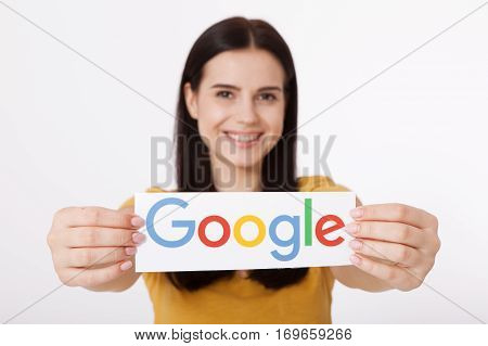 Kiev, Ukraine - August 22, 2016: Woman hands holding colorful Google logotype printed on paper on grey background.Google is USA multinational corporation.