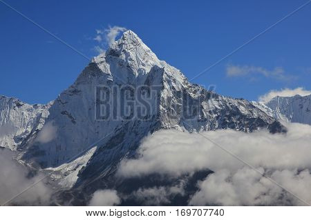 Peak of mount Ama Dablam reaching out of clouds. Scene in the Everest National Park Nepal.