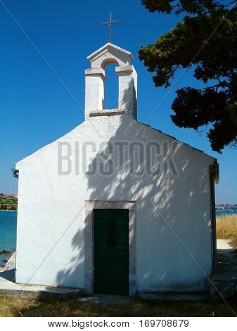 Photo of a little white chaple standing in the shadow of a tree