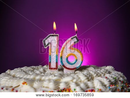 Tasty cake with candles for sixteenth birthday on purple background