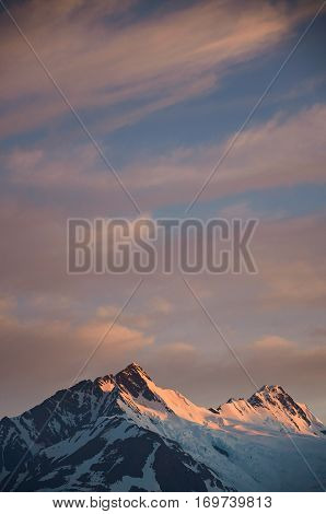 Mountain peak on sunset cloudy sky background. Orange dawn in alaska summit
