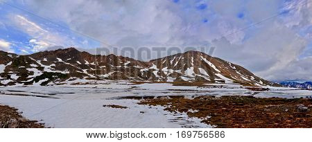 Storm clouds over mountanis and reflection in water. Snow thawing on Independence Pass. Aspen. Colorado. United States.