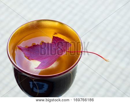 Red Maple Leaf In A Wooden Wine Cup On Tatami Map