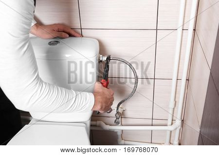 Plumber fixing water hose on toilet cistern