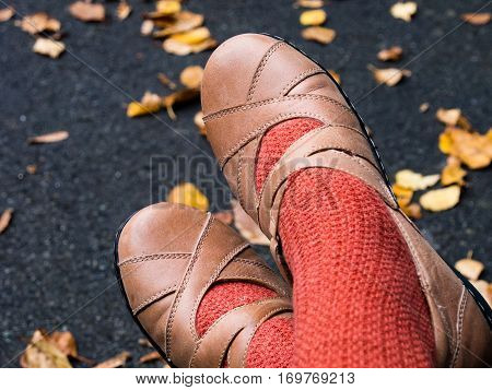 Woman's feet in autumn shoes against asphalt background