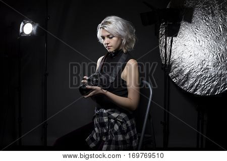 Creative female professional photographer in a strobe lighting studio. She portrays an independent self employed freelance entrepreneur. The image depicts the photography arts.