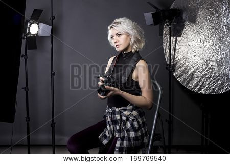 Creative female professional photographer in a strobe lighting studio. She portrays an independent self employed freelance entrepreneur. The image depicts the photography arts.