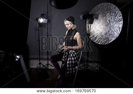 Creative female professional photographer in a strobe lighting studio. She portrays an independent self employed freelance entrepreneur. The image depicts the photography arts.