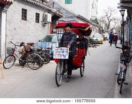 Beijing, China - March 8, 2015: Pedicab Carrying Passengers Along The Narrow Lane In Historic Hutong