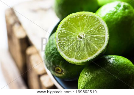 Heap of ripe organic limes cut in half in the sunlight,on vintage wood, ingredients for infused detox drinks, citrus, cleansing, health,diet