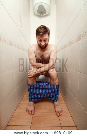 Man makes an effort on a toilet bowl.