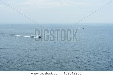 Three different ship floating in the sea at different speeds. Sea in this case, a huge lake Baikal. In the foreground is a small cruise liner ship. Behind are two hydrofoils.
