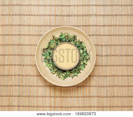 Plate with bath salt on green leaves over bamboo mat. Spa, health, treatment concept.  