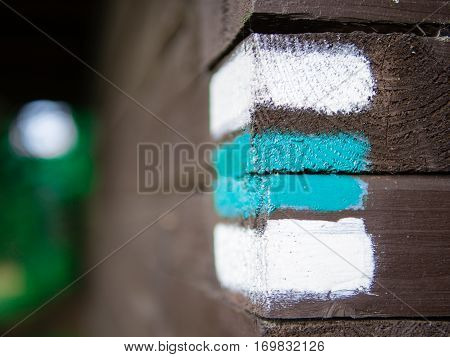 Blue and white hiking arrow sign on wooden wall corner, typical for czech tourism, providing guidence, touristic navigation or directions, copyspace with blurred background