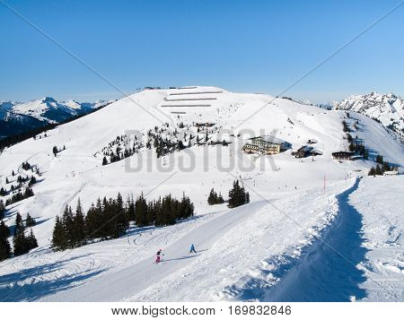 Downhill slope and apres ski mountain hut with restaurant terrace in Saalbach Hinterglemm Leogang winter resort, Tirol, Austria, Europe. Sunny day shot.