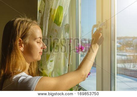 Girl is opening window and breathing fresh frosty air in snowy mountains