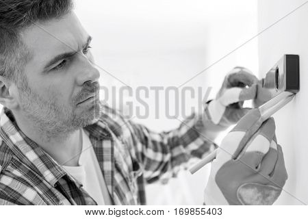 Mid-adult man marking on wall with level