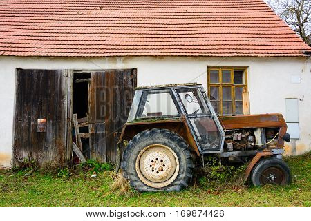 Old rusty tractor. Agricultural machine dilapidated front of the farm. Old iron. Tractor waiting to be scrapped. Abandoned farm.