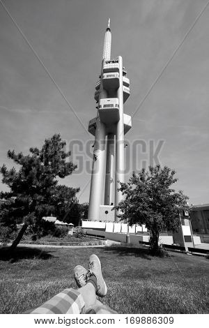 Low section of man relaxing in front of Zizkov Television Tower in Prague; Czech Republic