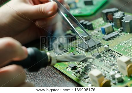 Male hands close up soldering a microchip