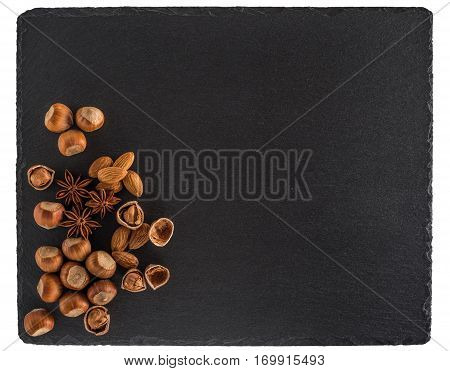 Nuts mix on a black slate board. Isolated on white background. Top view.