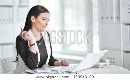 young brunette woman working at office, using laptop