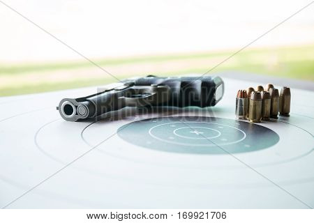 11 mm or .45 bullets on bullseye target with blurred pistol gun and copy space