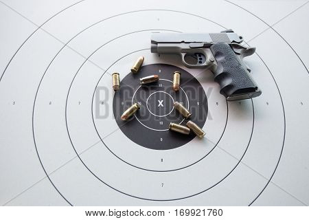 11 mm or .45 bullets on bullseye target with blurred pistol gun and copy space
