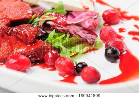 Salad with roasted duck fillet, berry sauce, cheese and fresh herbs