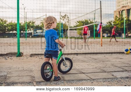 Active Blond Kid Boy Driving Bicycle In The Park Near The Sea. Toddler Child Dreaming And Having Fun