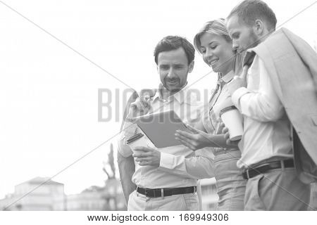 Low angle view of businesspeople using digital tablet against clear sky