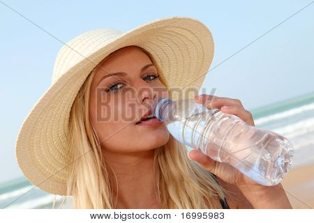 Closeup ผู้หญิงดื่มน้ำที่ชายหาด