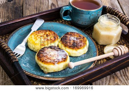 Pancakes with honey on vintage bowl on wooden tray. Studio Photo