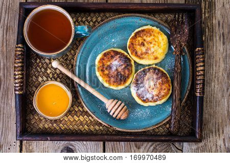 Pancakes with honey on vintage bowl on wooden tray. Studio Photo