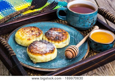 Pancakes with honey on vintage bowl on wooden tray. Studio Photo