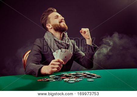 Successful pocker player enjoying his win at pocker table with chips and cards