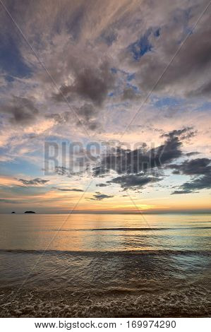 Coast of the sea at colorful sunset Koh Chang Thailand. Beach sunset is a golden sunset sky with a wave rolling to shore as the sun sets over the ocean horizon