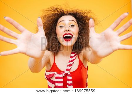 Bright model with open mouth extends at camera. Isolated orange background
