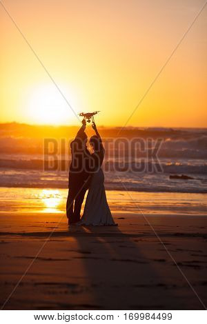 The bride and groom hold drone at sunset near ocena