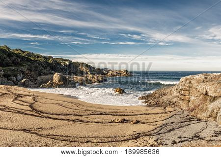 Waves Wash Onto A Small Sandy Cove Near Calvi In Corsica
