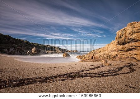 Waves Wash Onto A Small Sandy Cove Near Calvi In Corsica
