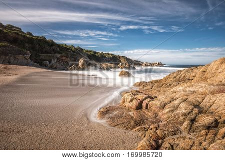 Waves Wash Onto A Small Sandy Cove Near Calvi In Corsica