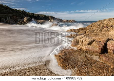 Waves Crash Onto A Small Sandy Cove Near Calvi In Corsica