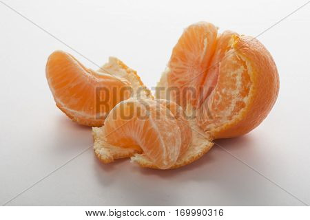Smal easy peeler orange partially peeled and split into pieces